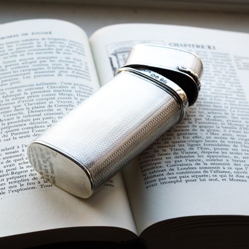 fig 2. An antique engine-turned solid silver cigar case featuring floral relief thumbpiece detailing and an engraved cartouche on the end.