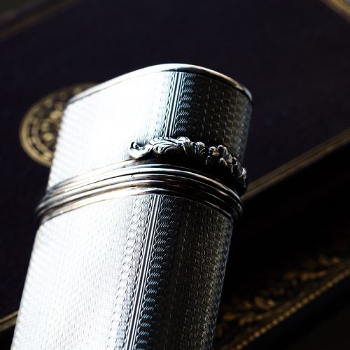 fig 4. An antique engine-turned solid silver cigar case featuring floral relief thumbpiece detailing and an engraved cartouche on the end.