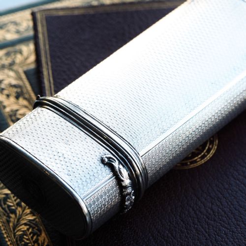 fig 5. An antique engine-turned solid silver cigar case featuring floral relief thumbpiece detailing and an engraved cartouche on the end.