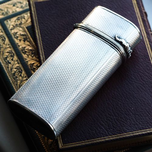 fig 6. An antique engine-turned solid silver cigar case featuring floral relief thumbpiece detailing and an engraved cartouche on the end.