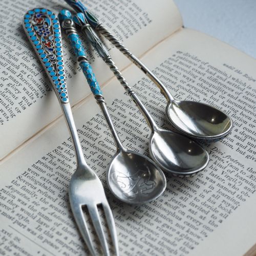 fig 6. A four-piece set of late 19th-century Russian silver and cloisonne enamel cutlery featuring three spoons and a fork with turquoise blue, white, and red floral motifs.
