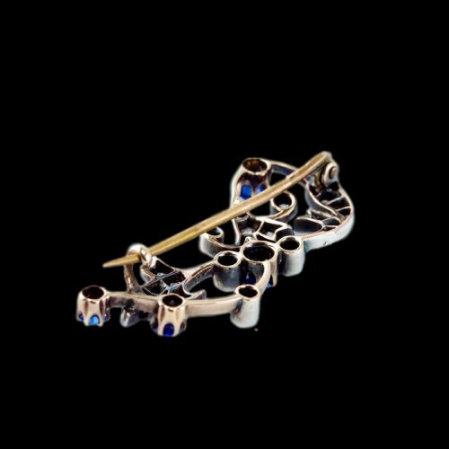 fig 8. An antique Victorian foliate scroll brooch crafted in gold and silver, set with circular blue sapphires and accent diamonds.