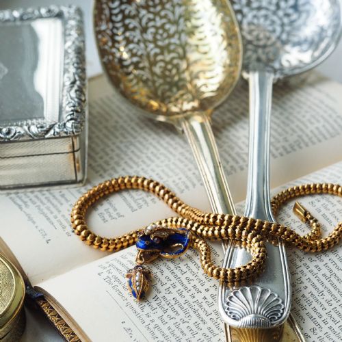fig 5. A Victorian 18-carat gold woven chain necklace featuring a blue enamel snake head set with seed pearls, small diamonds, and ruby eyes.