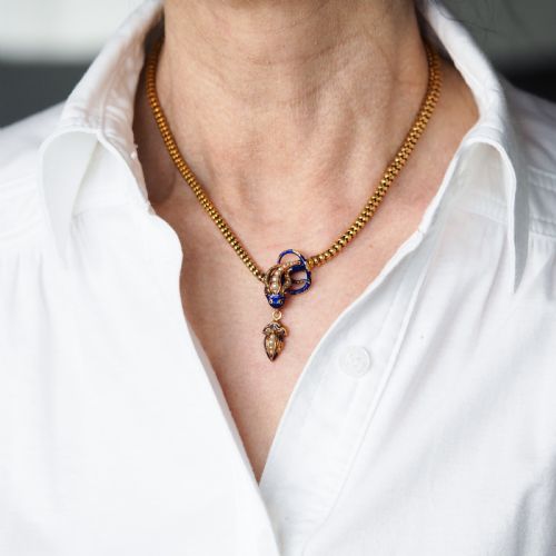 fig 8. A Victorian 18-carat gold woven chain necklace featuring a blue enamel snake head set with seed pearls, small diamonds, and ruby eyes.