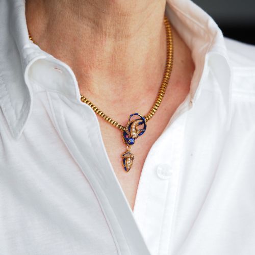 fig 9. A Victorian 18-carat gold woven chain necklace featuring a blue enamel snake head set with seed pearls, small diamonds, and ruby eyes.