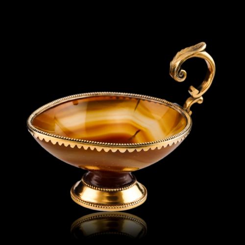 fig 6. A 19th-century carved brown banded agate cup featuring a silver-gilt rim, pedestal base, and an ornate scroll handle.