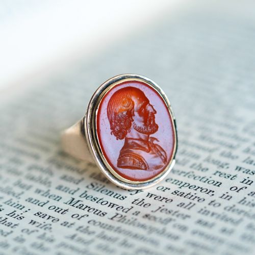fig 3. An antique gold signet ring featuring an oval red carnelian gemstone carved with the side profile portrait of a gentleman.