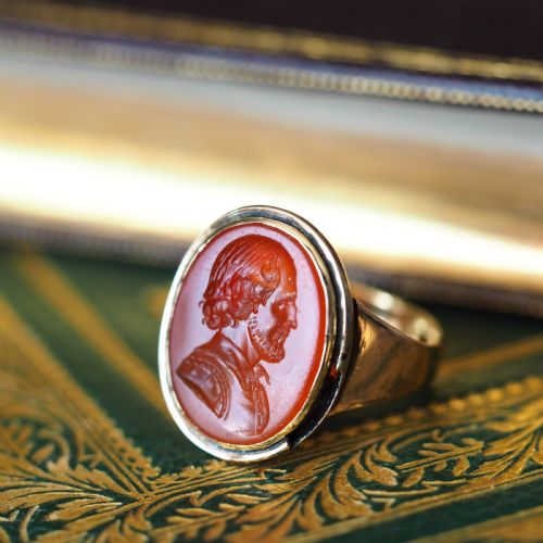fig 6. An antique gold signet ring featuring an oval red carnelian gemstone carved with the side profile portrait of a gentleman.