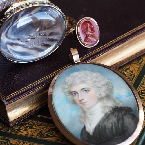 fig 1. An oval Georgian portrait miniature depicting a subject with light powdered hair set in a 14k gold frame with a top bail.