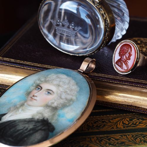 fig 2. An oval Georgian portrait miniature depicting a subject with light powdered hair set in a 14k gold frame with a top bail.