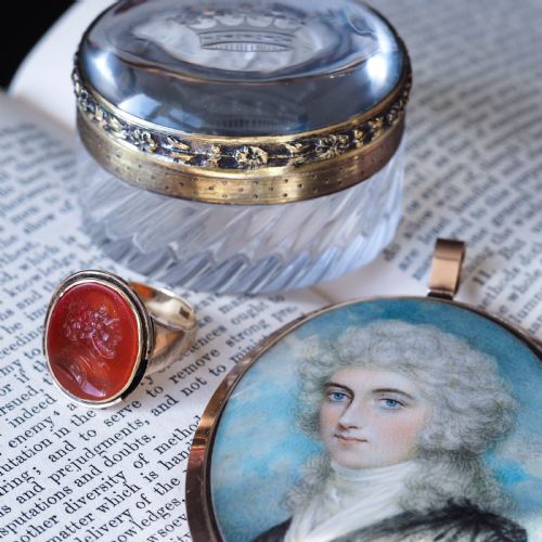 fig 3. An oval Georgian portrait miniature depicting a subject with light powdered hair set in a 14k gold frame with a top bail.