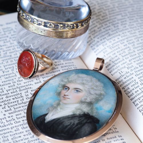 fig 4. An oval Georgian portrait miniature depicting a subject with light powdered hair set in a 14k gold frame with a top bail.