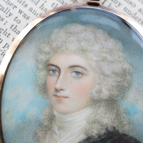 fig 6. An oval Georgian portrait miniature depicting a subject with light powdered hair set in a 14k gold frame with a top bail.