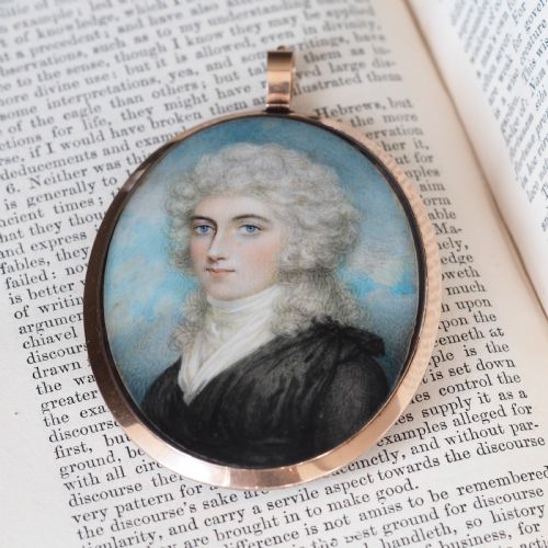 fig 8. An oval Georgian portrait miniature depicting a subject with light powdered hair set in a 14k gold frame with a top bail.