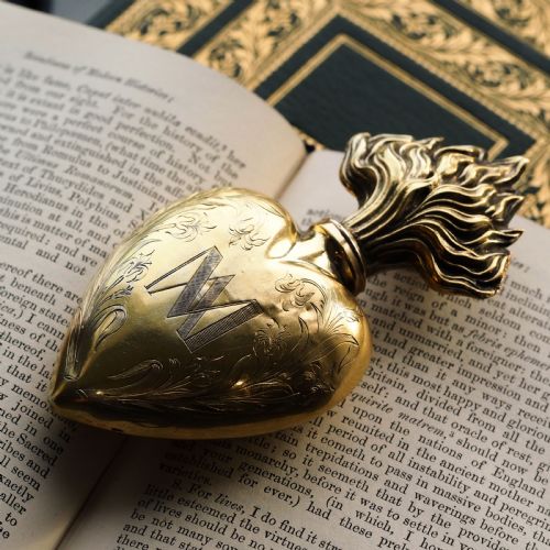 fig 7. A 19th-century French silver-gilt heart-shaped scent bottle featuring an engraved monogram, foliate scrollwork, and a flame-shaped stopper.