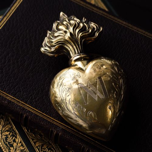 fig 8. A 19th-century French silver-gilt heart-shaped scent bottle featuring an engraved monogram, foliate scrollwork, and a flame-shaped stopper.