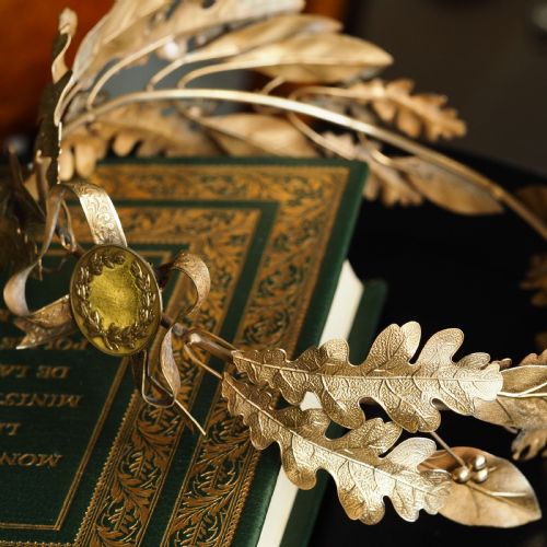 fig 7. A 19th-century silver gilt foliate crown featuring detailed oak leaves, acorns, laurel leaves, and a central ribbon bow medallion.
