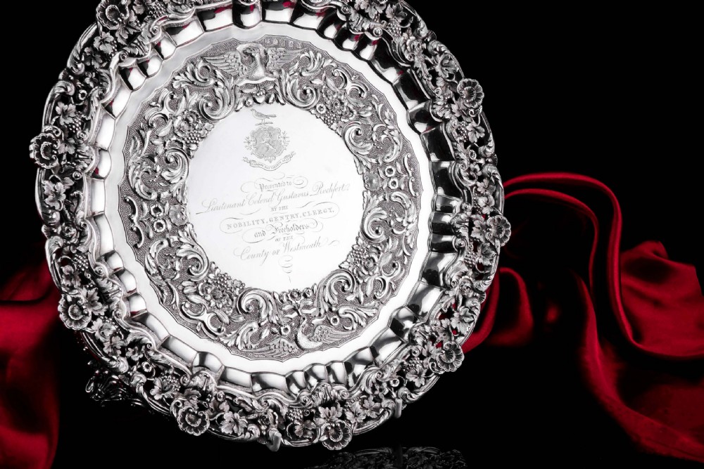 A circular Georgian sterling silver salver featuring an intricately detailed cast floral border and central inscription engraving. View II
