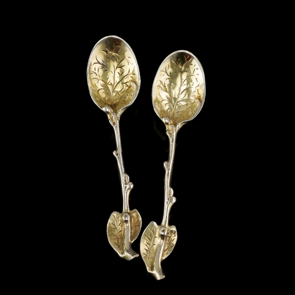 A pair of Victorian silver-gilt serving spoons designed in a naturalistic motif with textured twig handles and leaf-engraved bowls. View V