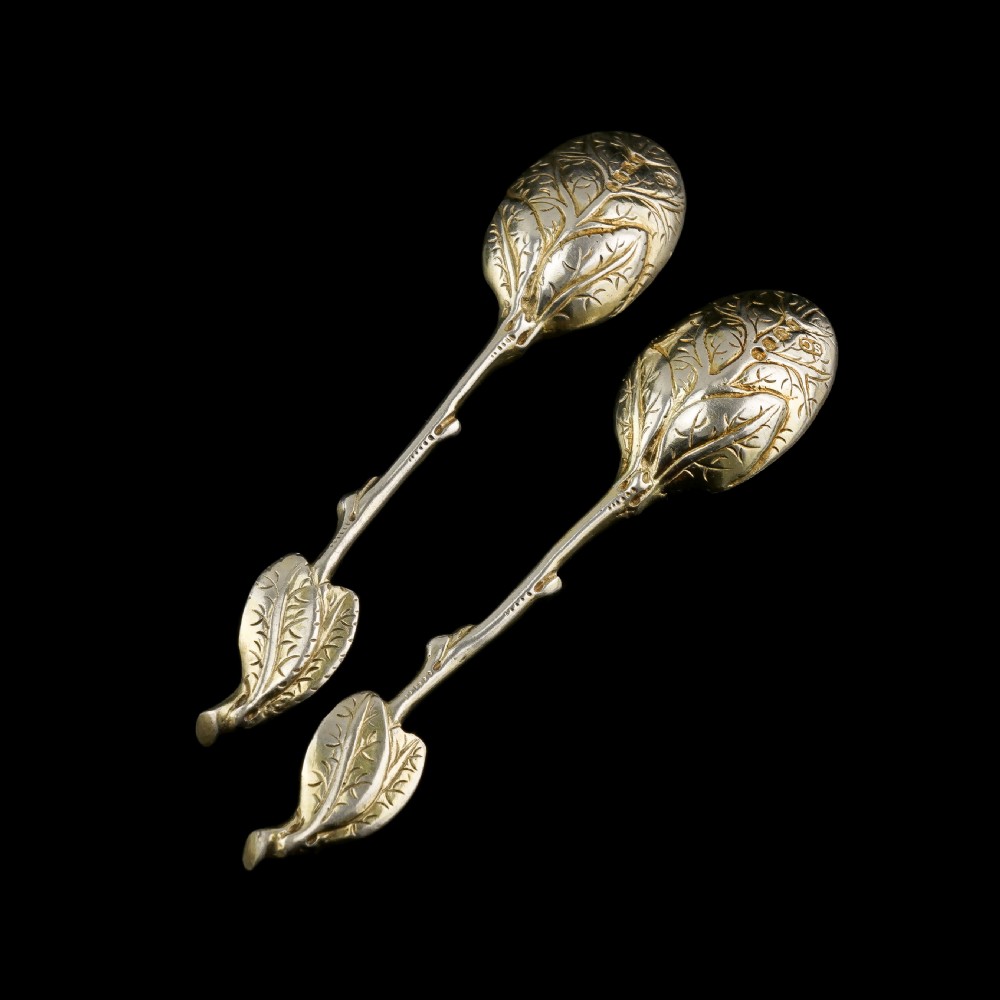 A pair of Victorian silver-gilt serving spoons designed in a naturalistic motif with textured twig handles and leaf-engraved bowls. View VI