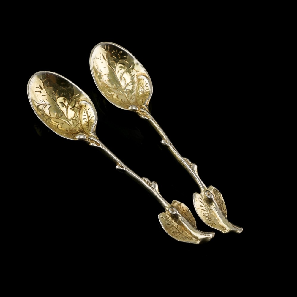 A pair of Victorian silver-gilt serving spoons designed in a naturalistic motif with textured twig handles and leaf-engraved bowls. View VII