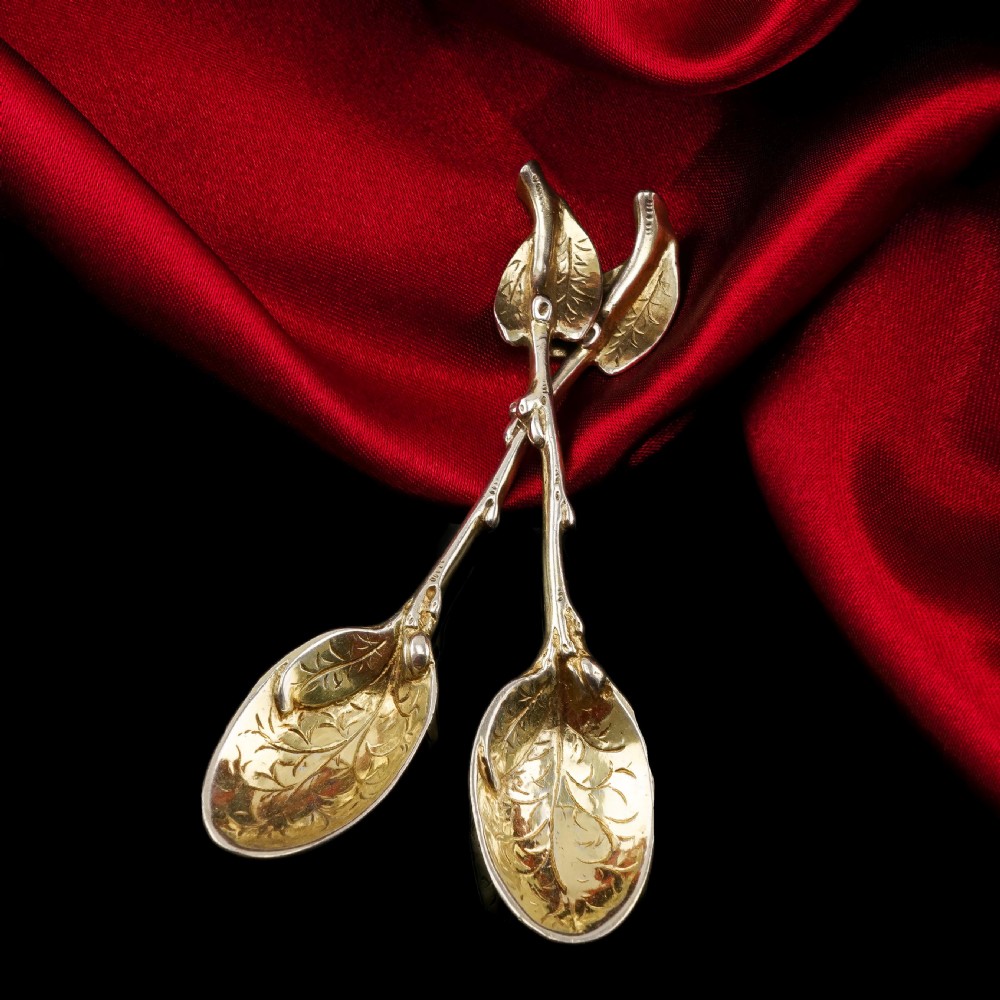 A pair of Victorian silver-gilt serving spoons designed in a naturalistic motif with textured twig handles and leaf-engraved bowls. View X