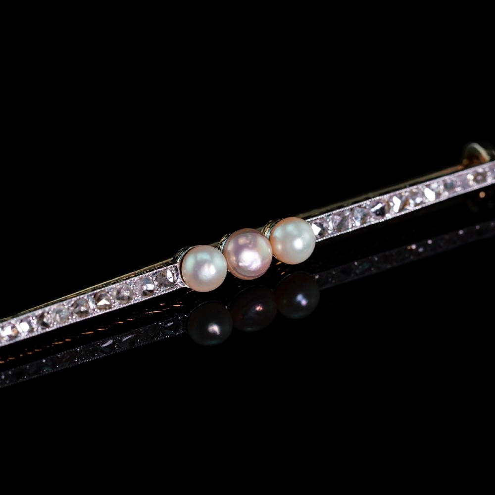 An antique platinum and gold linear bar brooch set with diamonds and three central pearls, featuring a soft pink pearl in the centre. View VI