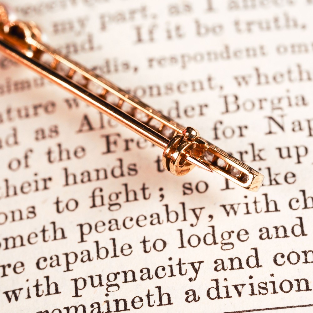 An antique platinum and gold linear bar brooch set with diamonds and three central pearls, featuring a soft pink pearl in the centre. View XIII