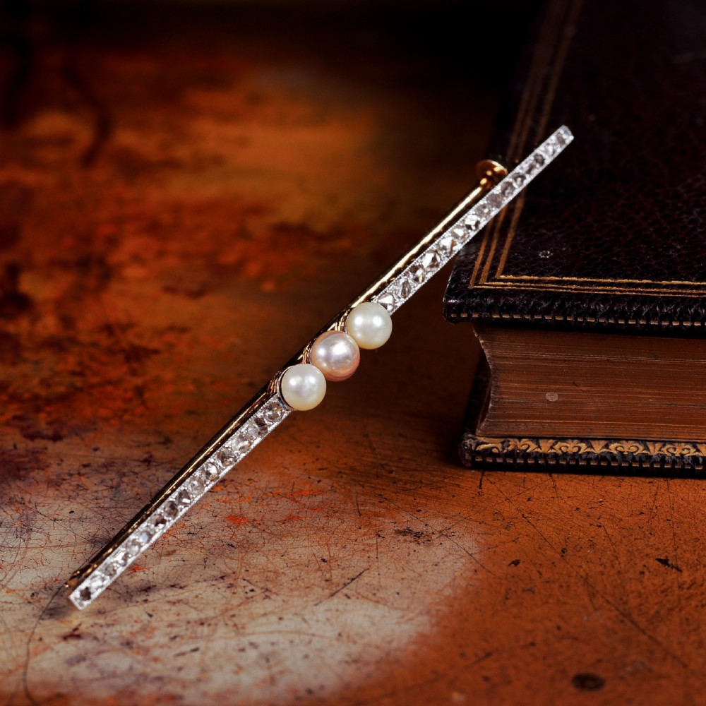 An antique platinum and gold linear bar brooch set with diamonds and three central pearls, featuring a soft pink pearl in the centre. View XV