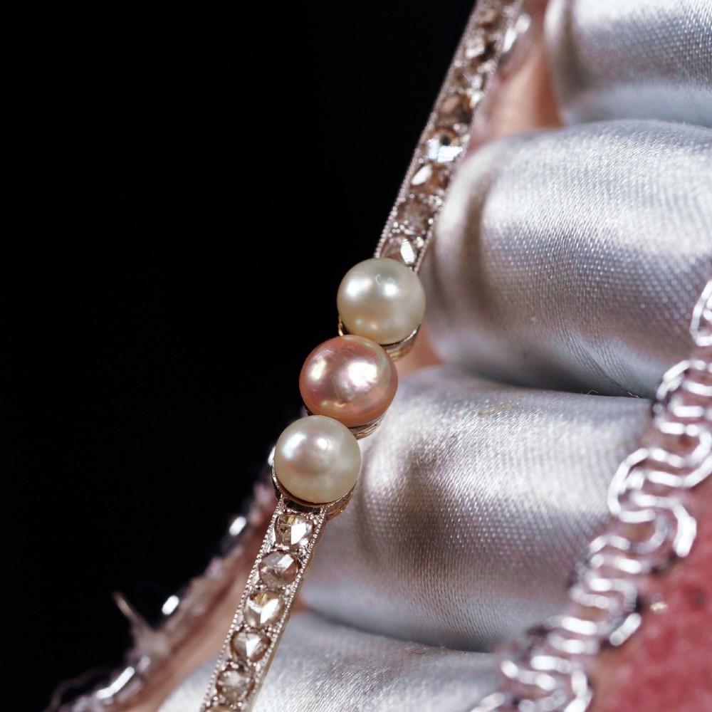 An antique platinum and gold linear bar brooch set with diamonds and three central pearls, featuring a soft pink pearl in the centre. View XVI