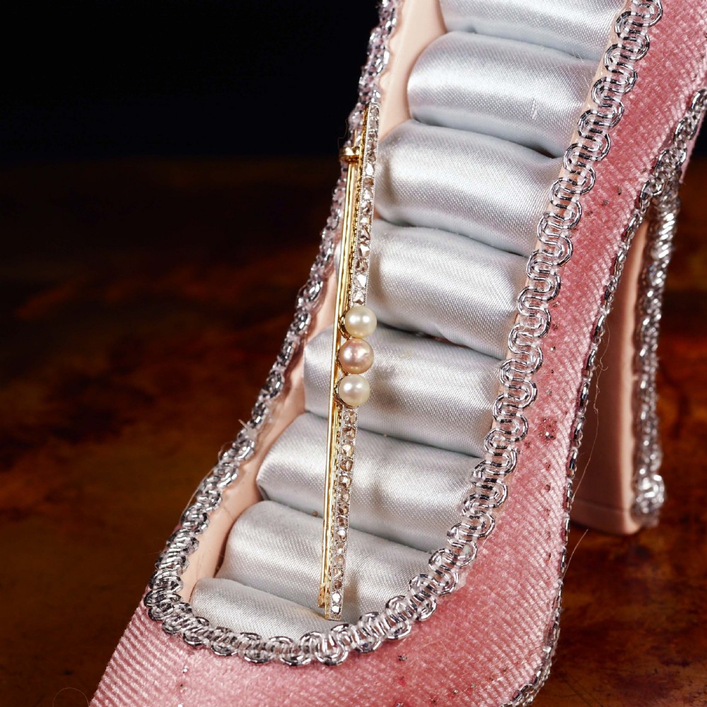 An antique platinum and gold linear bar brooch set with diamonds and three central pearls, featuring a soft pink pearl in the centre. View XVII
