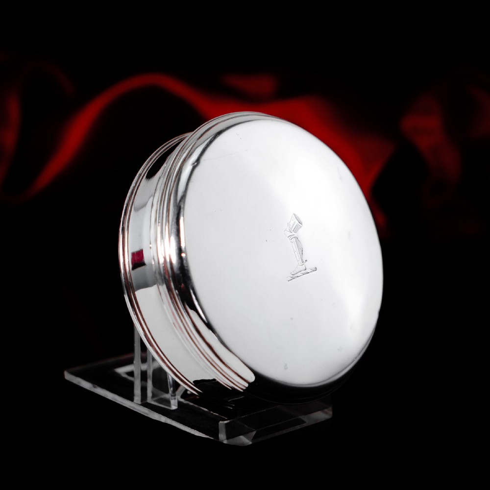 A circular Georgian sterling silver tobacco box featuring a polished flat cover hand-engraved with a crest. View VIII