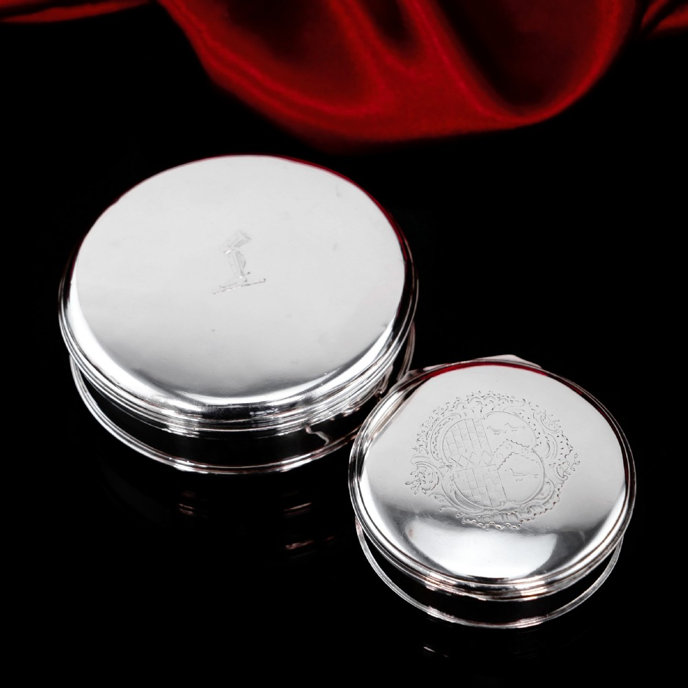 A circular Georgian sterling silver tobacco box featuring a polished flat cover hand-engraved with a crest. View XVII