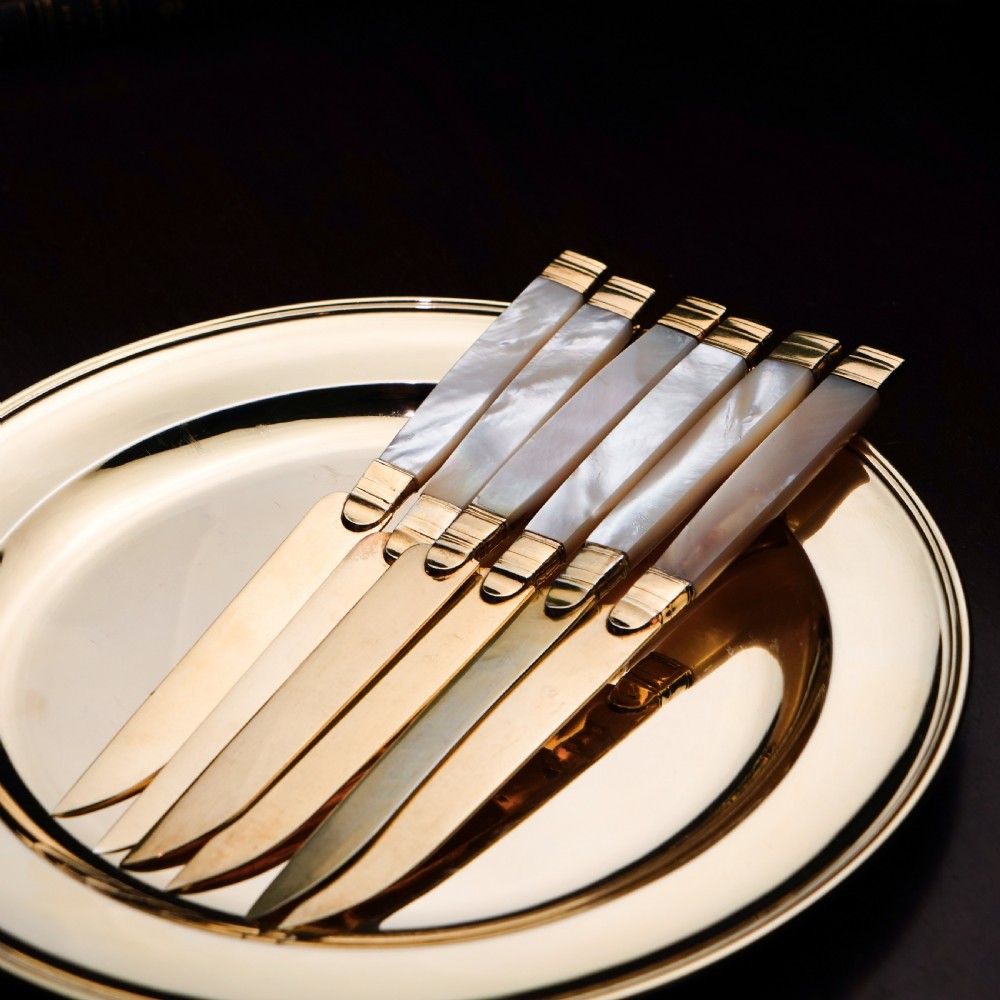 A set of six 19th-century fruit knives featuring silver-gilt blades and mother-of-pearl handles inlaid with small shield motifs. View VI