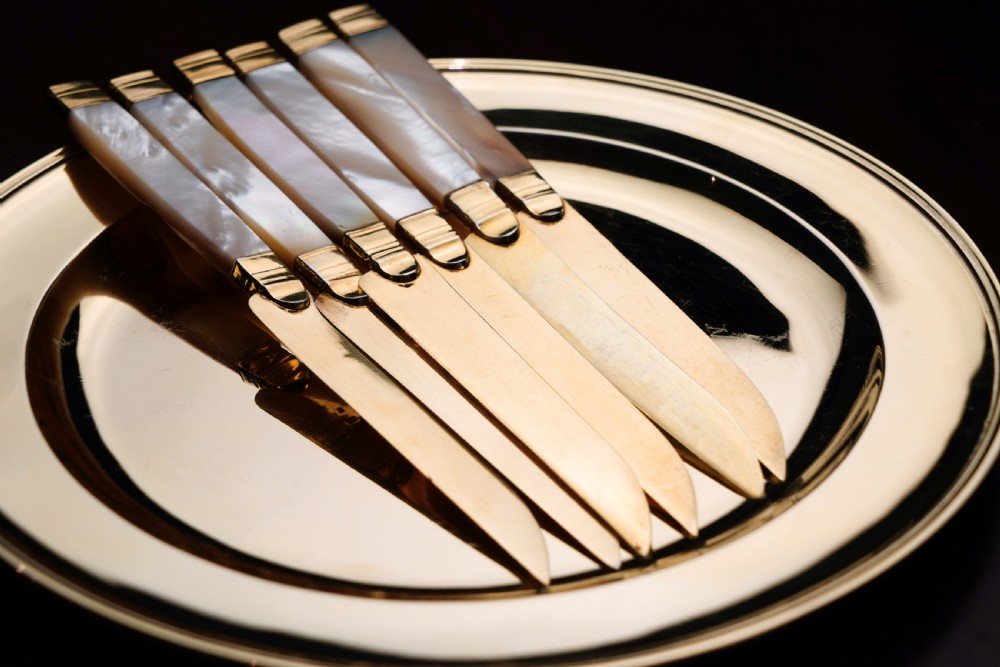 A set of six 19th-century fruit knives featuring silver-gilt blades and mother-of-pearl handles inlaid with small shield motifs. View VII