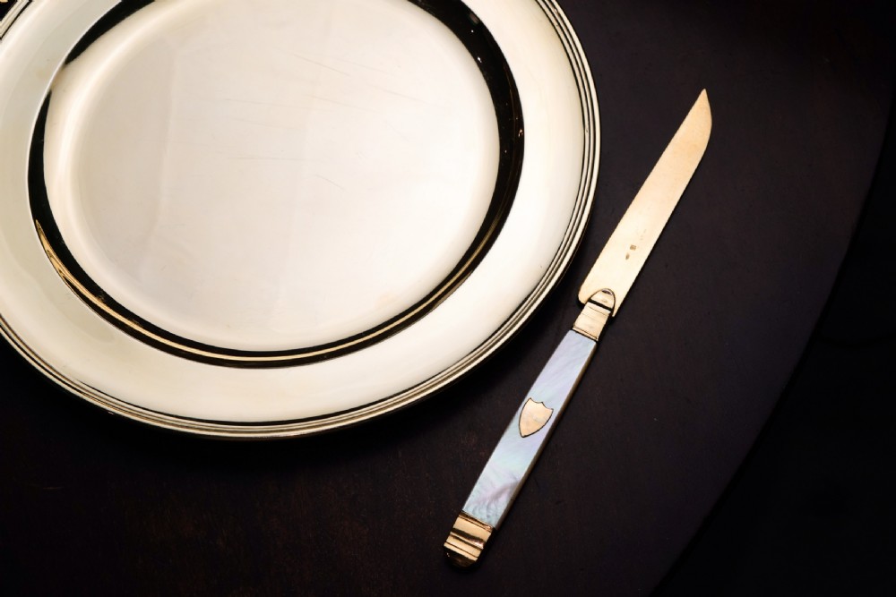 A set of six 19th-century fruit knives featuring silver-gilt blades and mother-of-pearl handles inlaid with small shield motifs. View IX