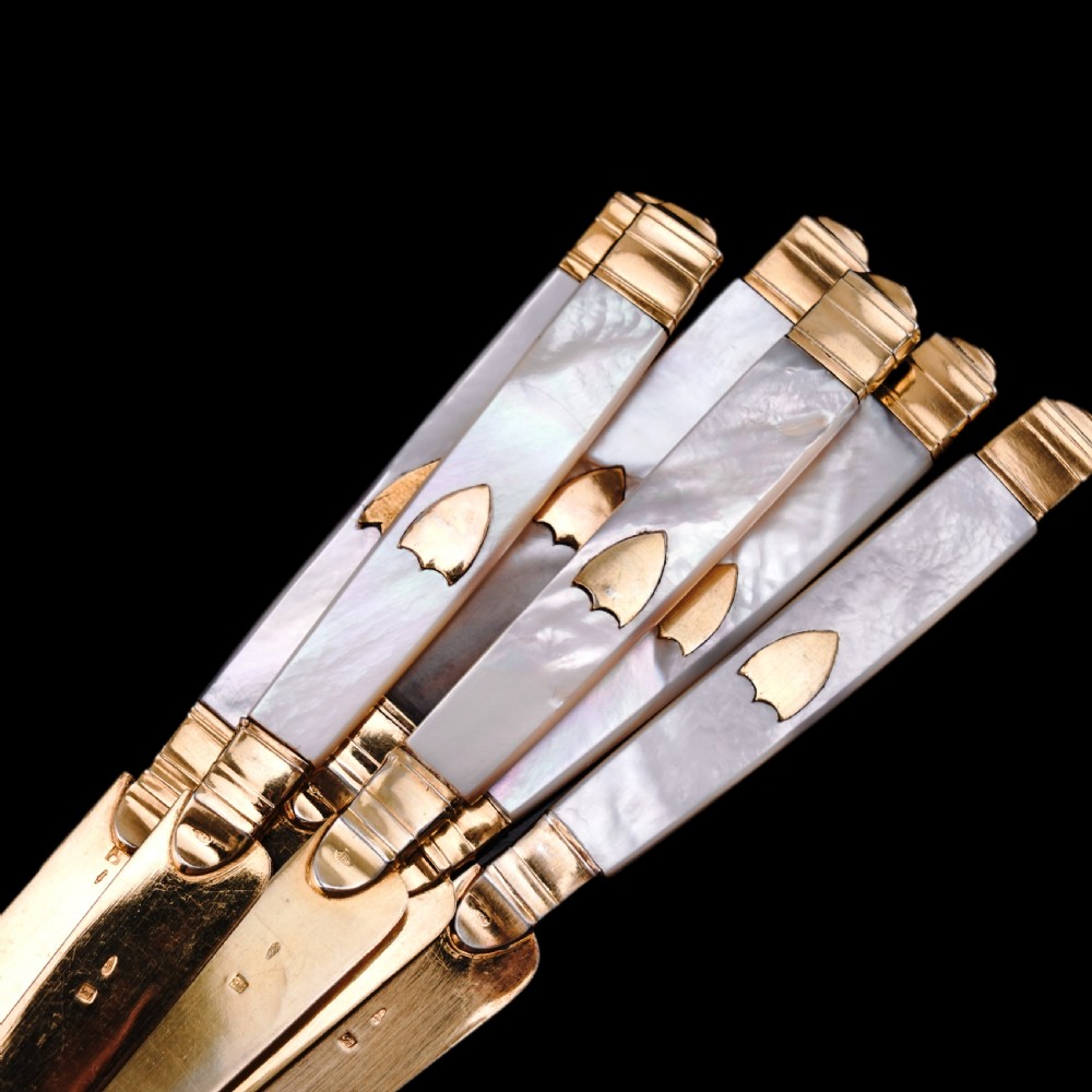 A set of six 19th-century fruit knives featuring silver-gilt blades and mother-of-pearl handles inlaid with small shield motifs. View XV