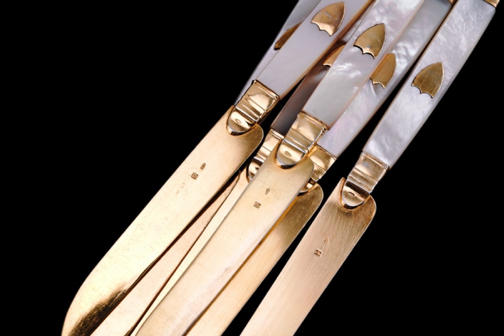 A set of six 19th-century fruit knives featuring silver-gilt blades and mother-of-pearl handles inlaid with small shield motifs. View XVI