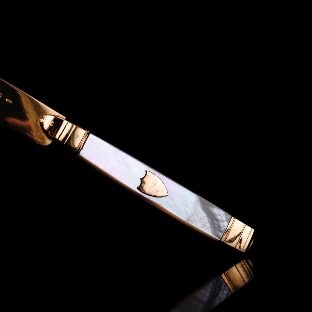 A set of six 19th-century fruit knives featuring silver-gilt blades and mother-of-pearl handles inlaid with small shield motifs. View XVIII
