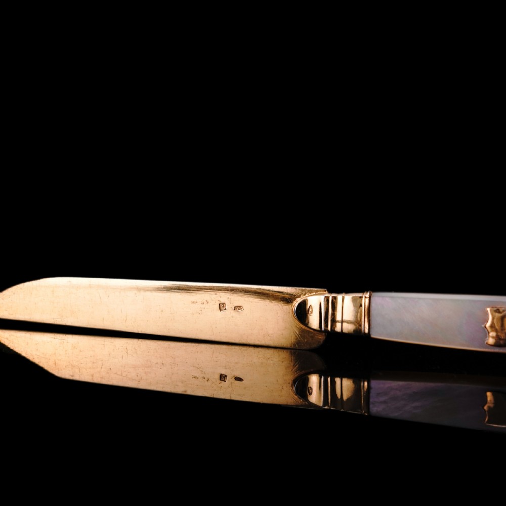 A set of six 19th-century fruit knives featuring silver-gilt blades and mother-of-pearl handles inlaid with small shield motifs. View XIX