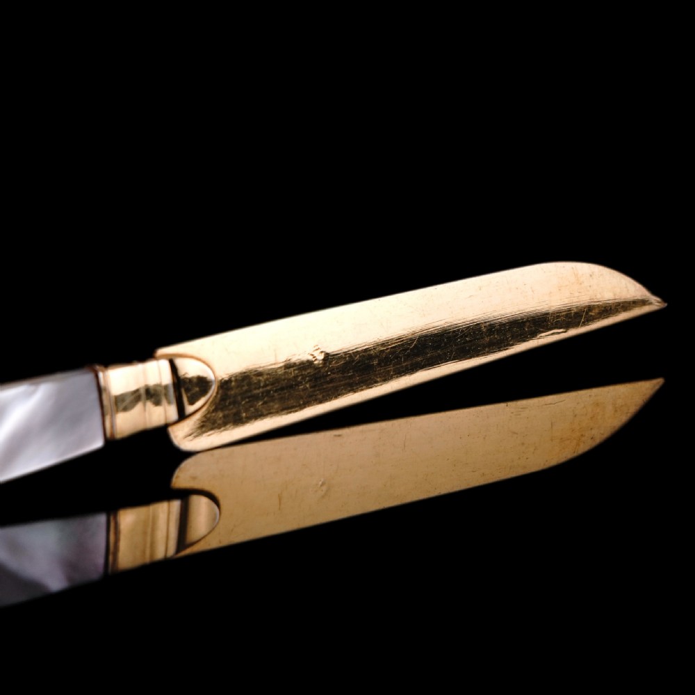 A set of six 19th-century fruit knives featuring silver-gilt blades and mother-of-pearl handles inlaid with small shield motifs. View XXII
