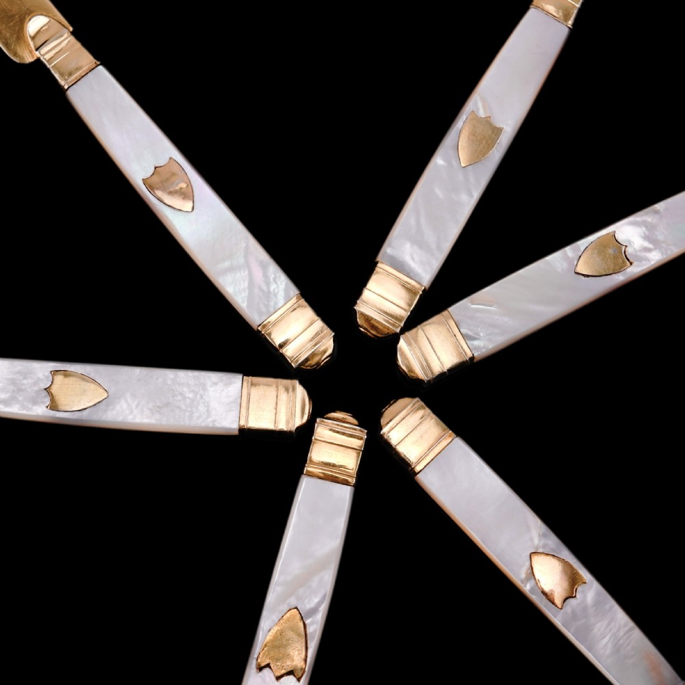 A set of six 19th-century fruit knives featuring silver-gilt blades and mother-of-pearl handles inlaid with small shield motifs. View XXIII