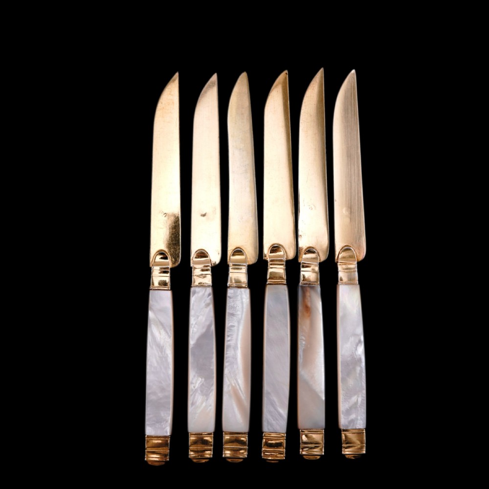 A set of six 19th-century fruit knives featuring silver-gilt blades and mother-of-pearl handles inlaid with small shield motifs. View XXV
