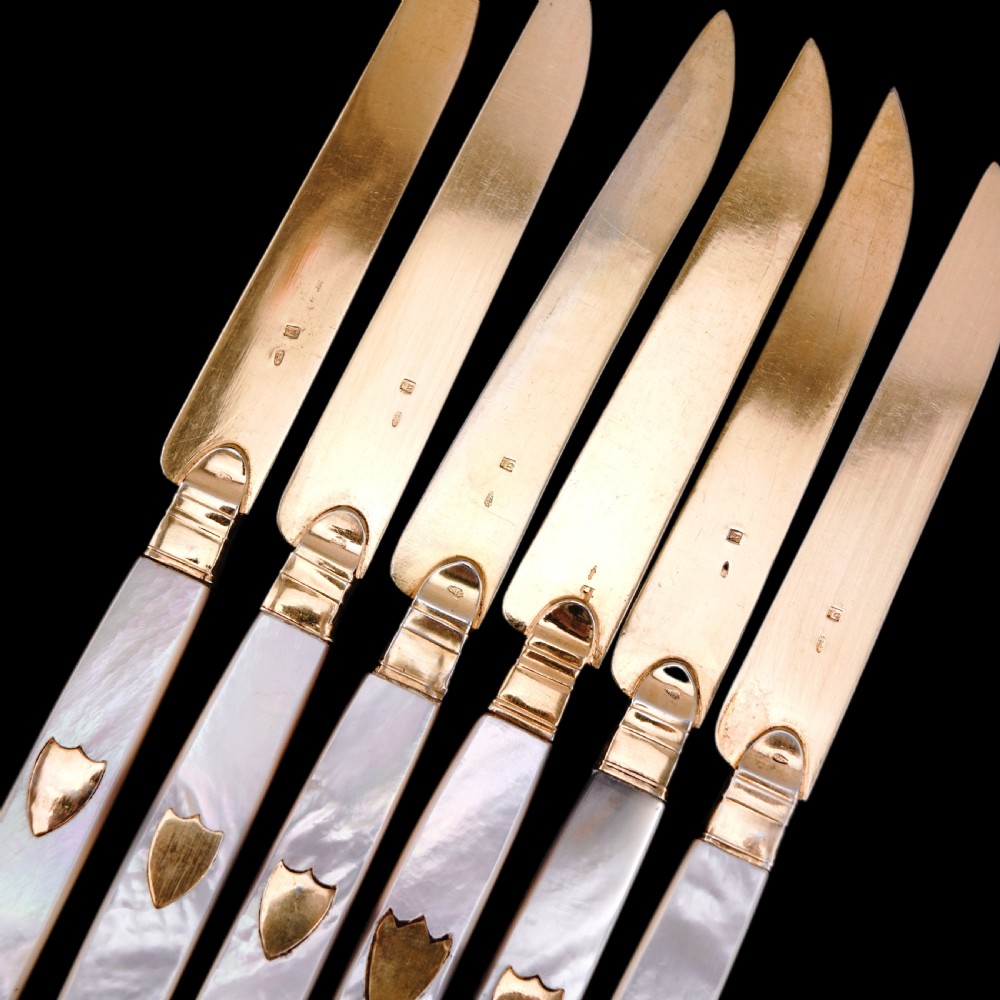A set of six 19th-century fruit knives featuring silver-gilt blades and mother-of-pearl handles inlaid with small shield motifs. View XXVI