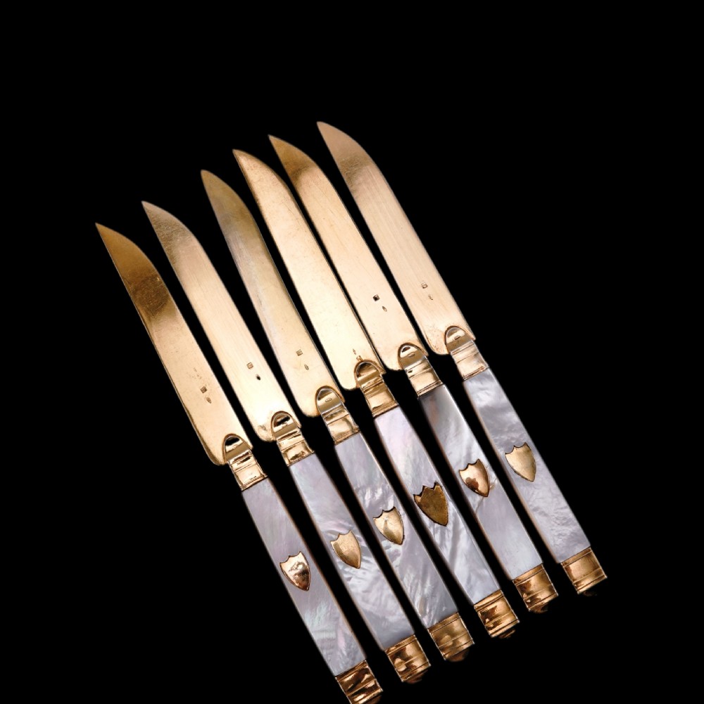 A set of six 19th-century fruit knives featuring silver-gilt blades and mother-of-pearl handles inlaid with small shield motifs. View XXVII