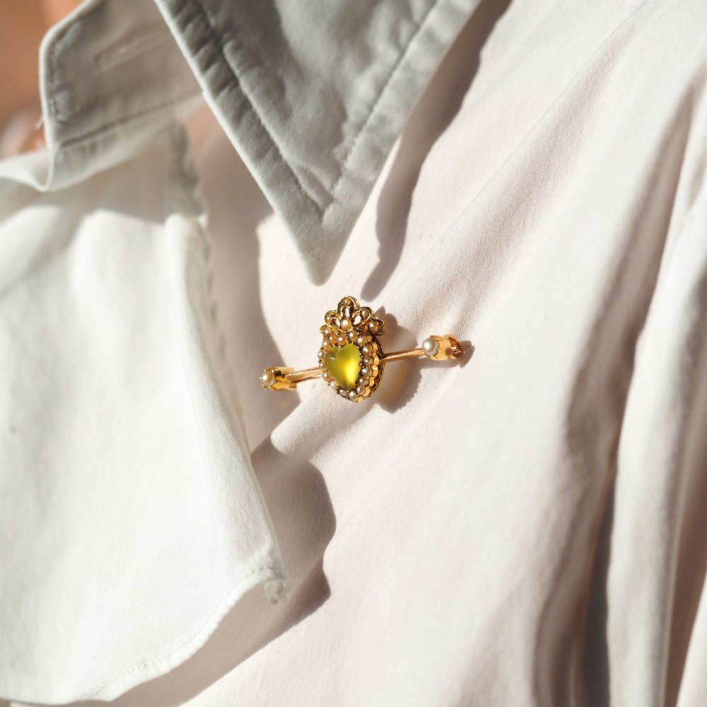 A late Victorian 15ct gold bar brooch featuring a central heart-shaped green chalcedony cabochon framed by seed pearls. View V