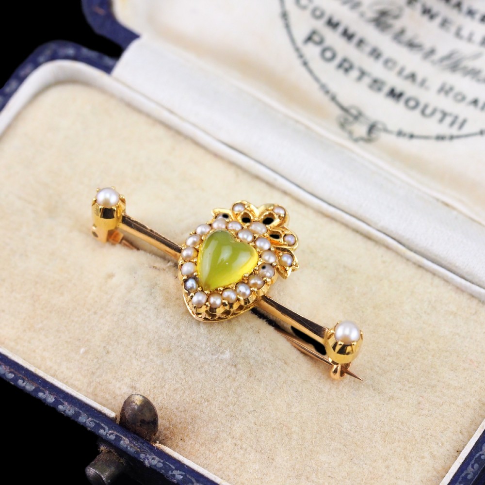 A late Victorian 15ct gold bar brooch featuring a central heart-shaped green chalcedony cabochon framed by seed pearls. View X