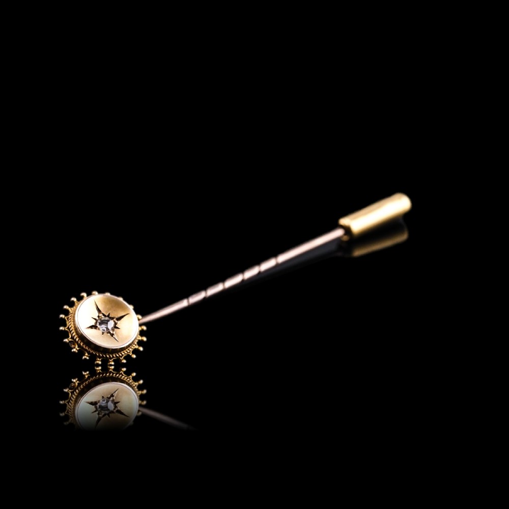 A Victorian 14ct gold stick pin featuring a round head with a star-set diamond and a beaded granulated outer border. View II