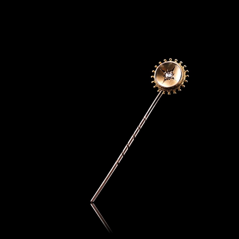 A Victorian 14ct gold stick pin featuring a round head with a star-set diamond and a beaded granulated outer border. View IV