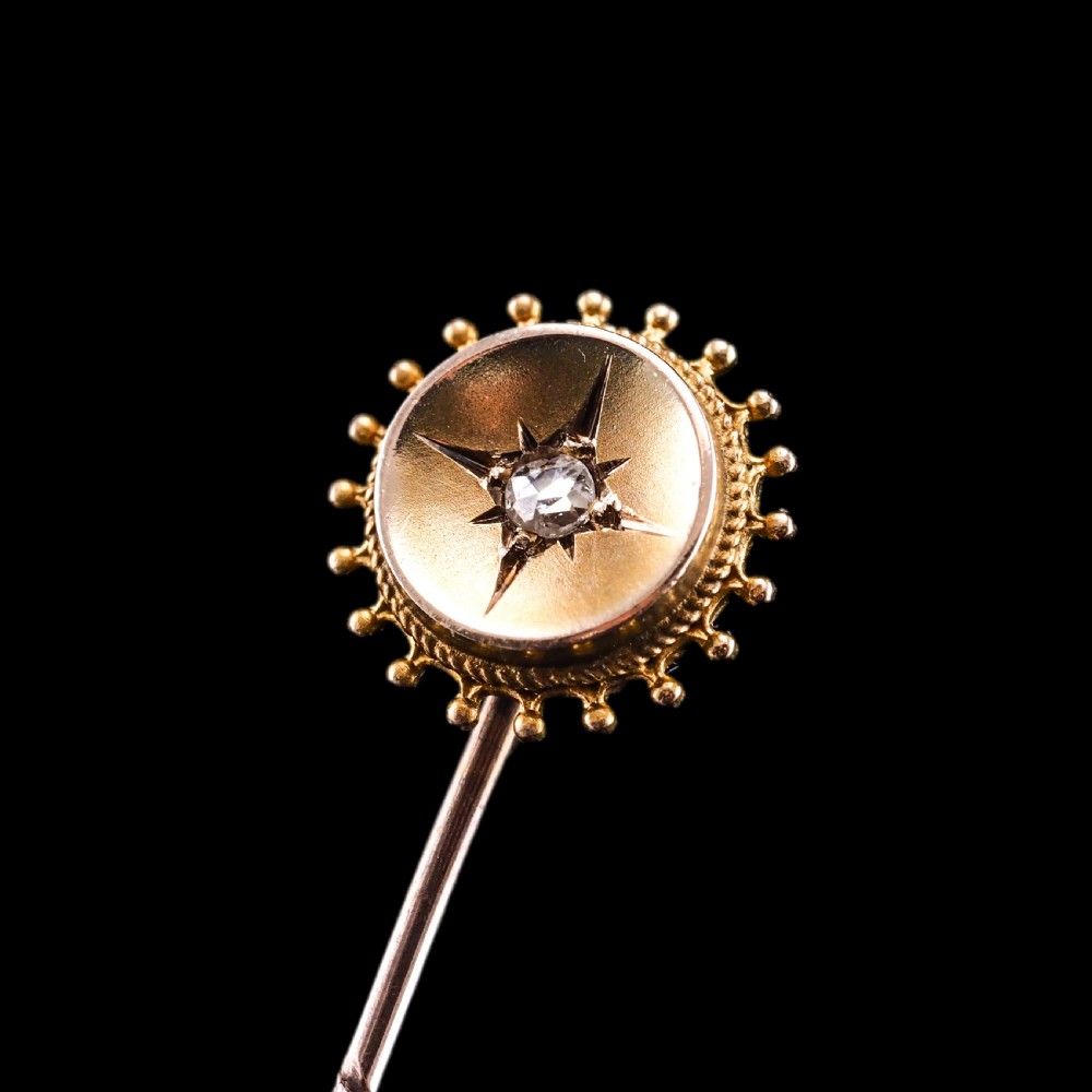 A Victorian 14ct gold stick pin featuring a round head with a star-set diamond and a beaded granulated outer border. View VII
